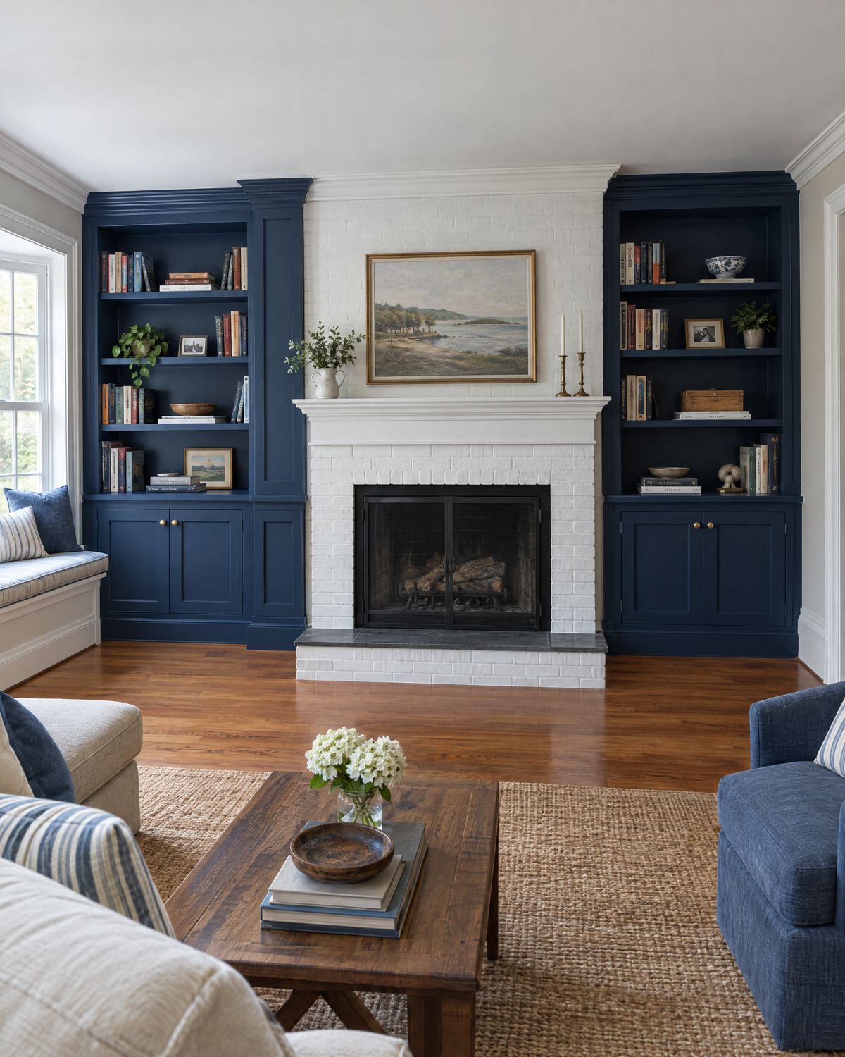 Navy built-in bookshelves on both sides of a white brick fireplace