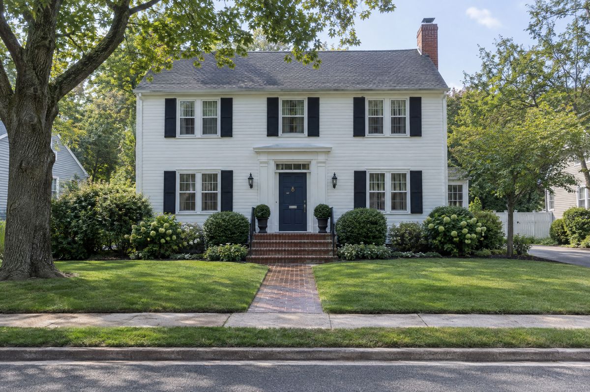 White two-story colonial house with black shutters and a front walk