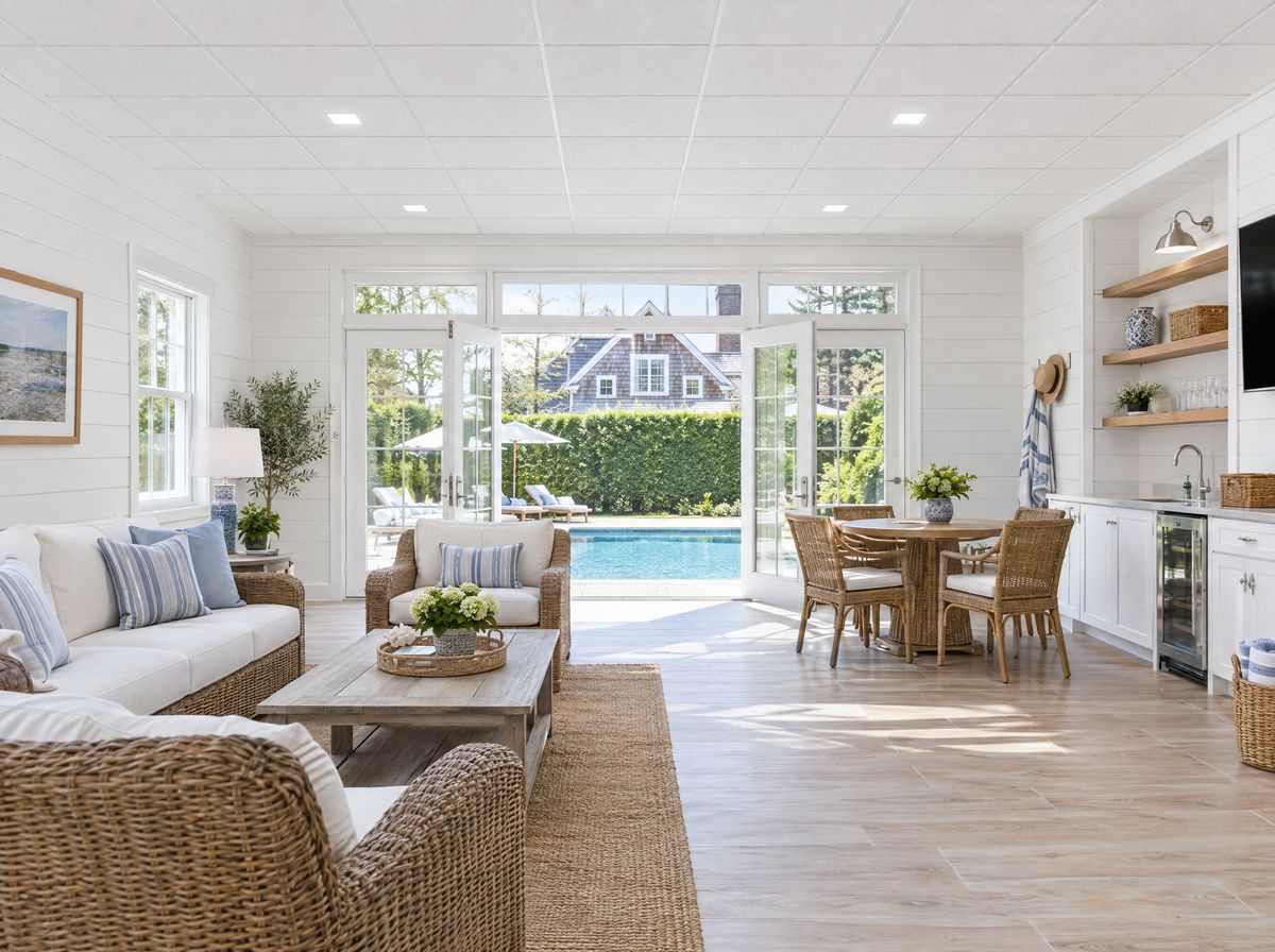 Bright pool house with a clean white drop ceiling and recessed lights opening onto a pool