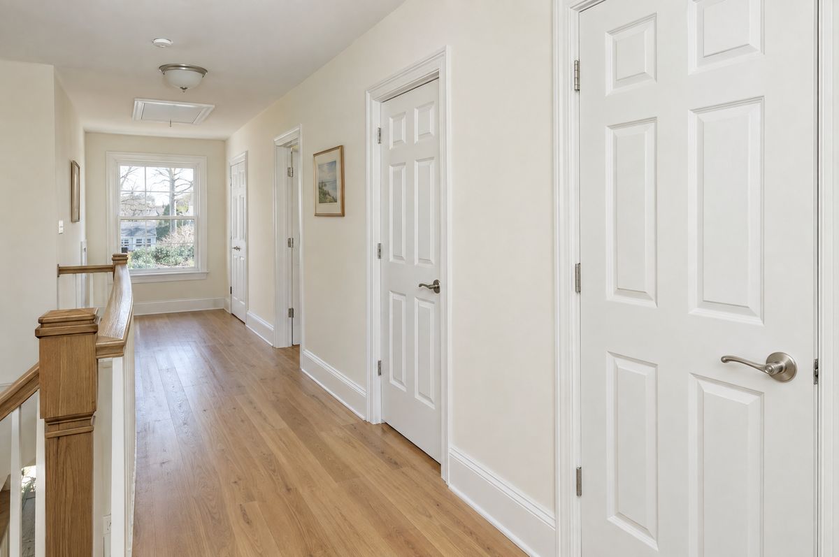 Hallway with a row of white paneled interior doors and matching trim