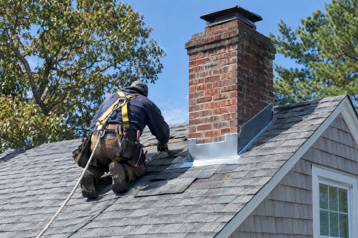 Close-up of hands nailing a new asphalt shingle into an older roof