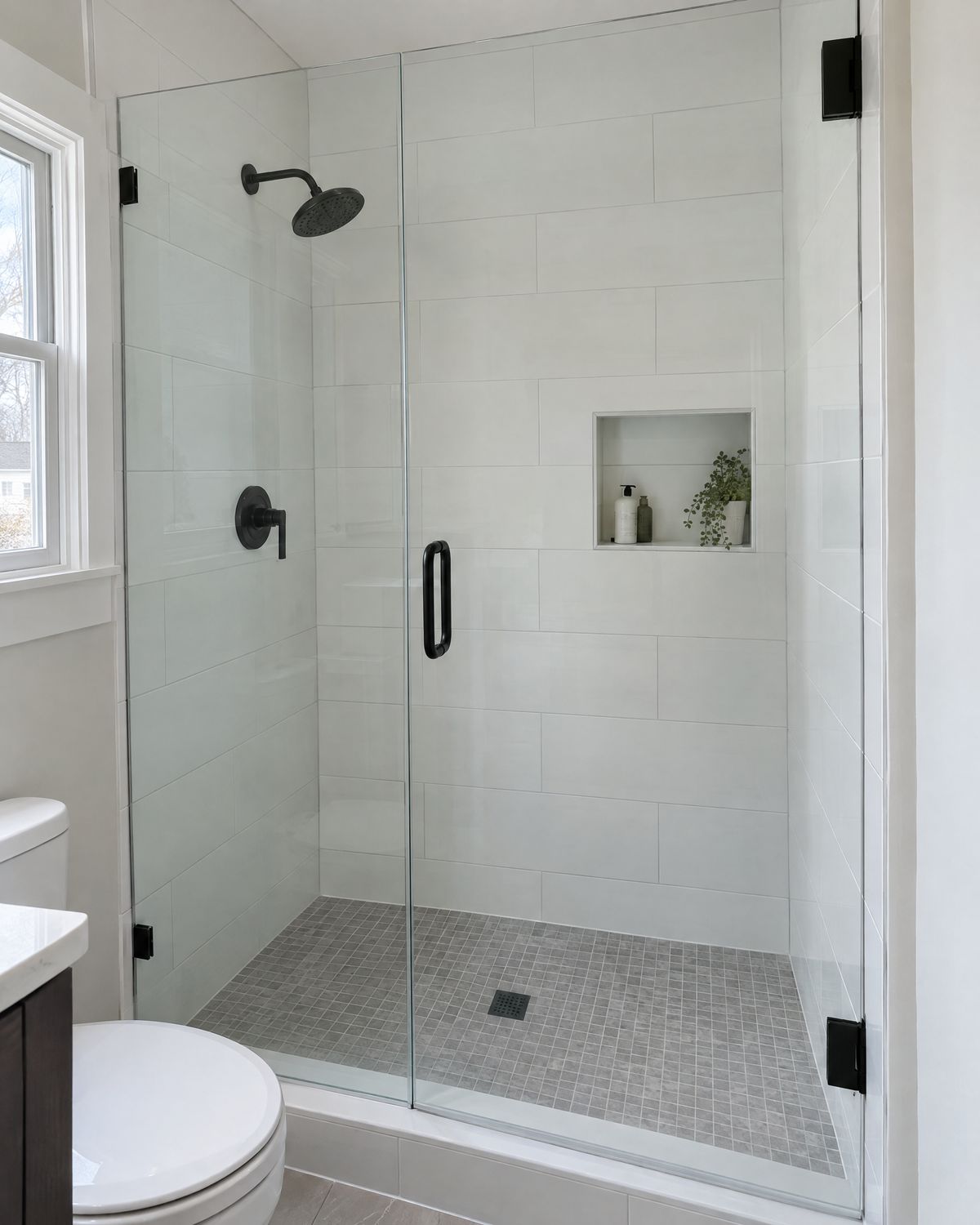 Tiled walk-in shower with large gray tiles and a glass panel