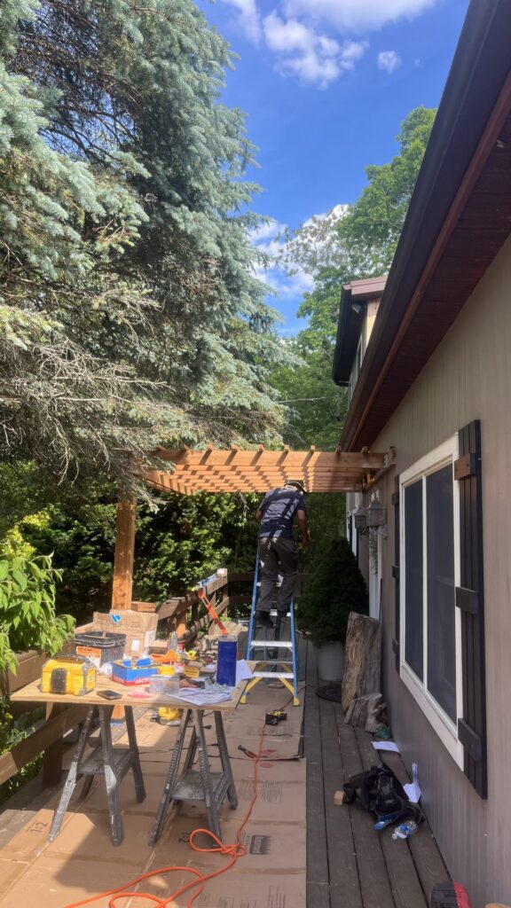 Crew building a wood pergola over a backyard deck