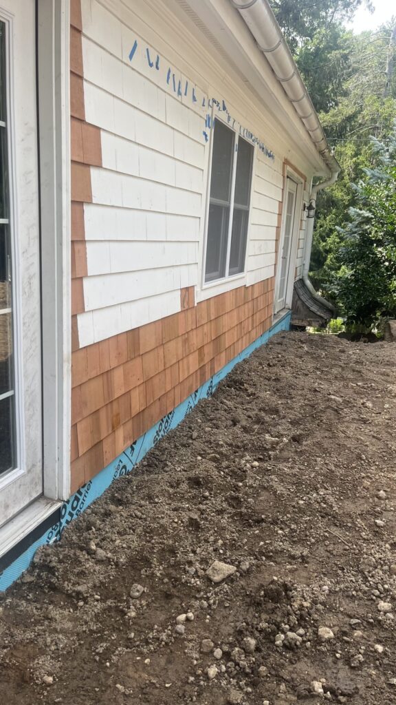 Cedar shingles on the lower wall of a house corner, ready for paint