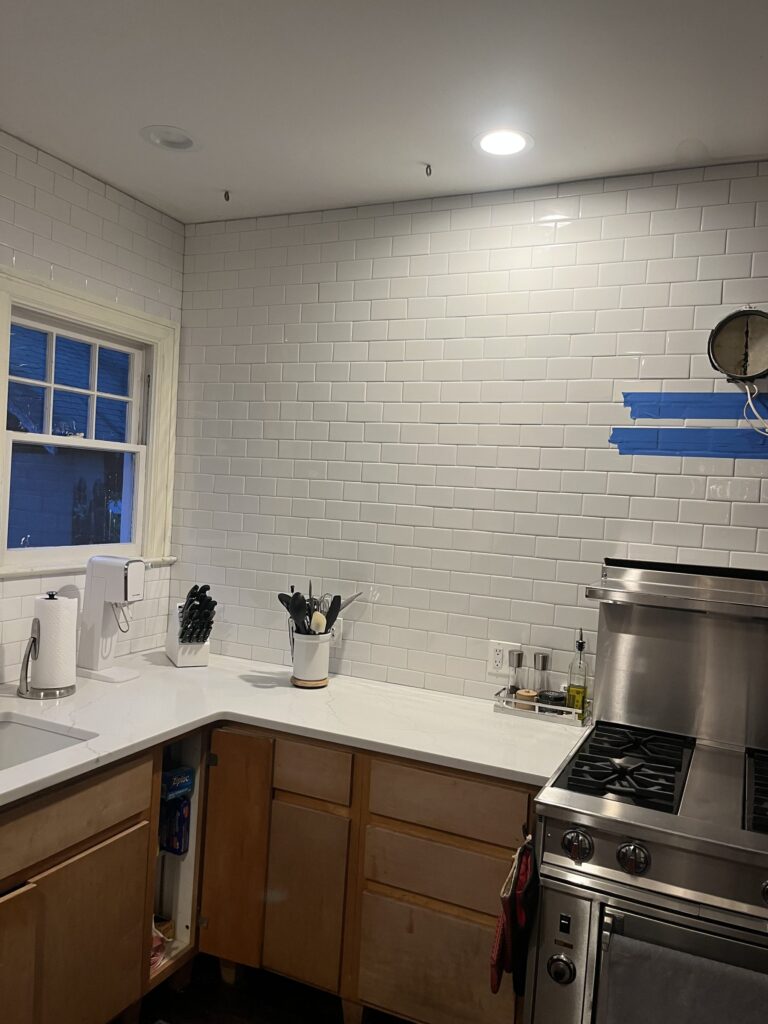 Finished kitchen corner with white subway tile from counter to ceiling