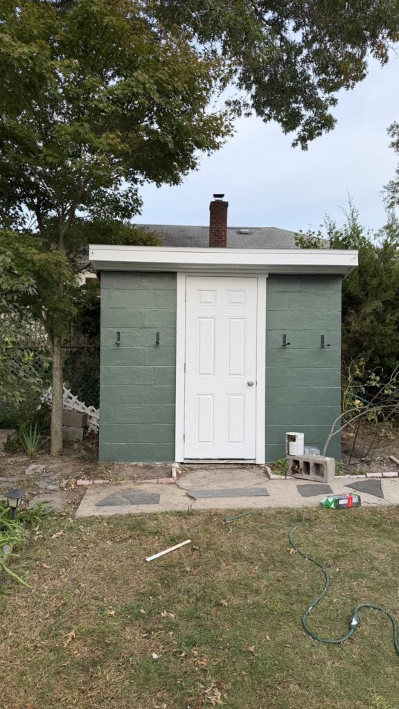 Backyard shed after repairs: fresh green paint, new white door and new trim